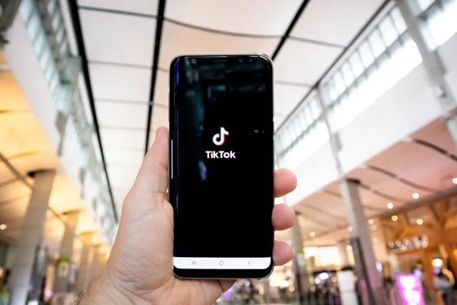 Hand holding a phone that shows the TikTok logo.